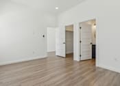 Thumbnail 11 of 48 - A white room with a wooden floor and three open doors.