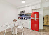 Thumbnail 15 of 38 - a small kitchen with a red refrigerator and a table and chairs