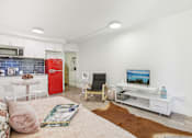 Thumbnail 5 of 38 - a living room with a couch and a kitchen with a red refrigerator