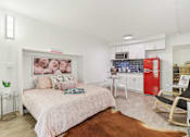 Thumbnail 13 of 38 - a bedroom with a bed and a kitchen with a red refrigerator