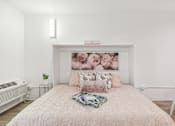 Thumbnail 9 of 38 - a bedroom with a bed and a painting of roses on the wall