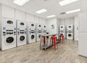 Thumbnail 11 of 38 - a laundry room with a row of washing machines and red stools