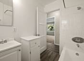 Thumbnail 8 of 10 - A white bathroom with a white sink and a white tub.