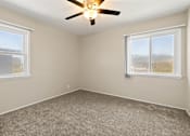 Thumbnail 7 of 10 - A room with a ceiling fan and two windows.