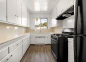 Thumbnail 5 of 23 - a kitchen with white cabinets and black appliances