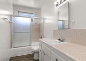 Thumbnail 10 of 17 - A bathroom with a toilet, sink, and a shower with a glass door.