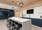 Thumbnail 25 of 60 - A modern bar area with a white counter and black stools.