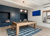 Thumbnail 26 of 60 - A pool table in a room with a blue couch and a television.
