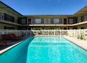 Thumbnail 23 of 28 - A swimming pool in front of a building with lounge chairs on the side.