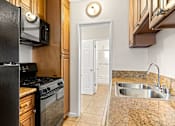 Thumbnail 17 of 28 - A kitchen with a black fridge, microwave, and stove.