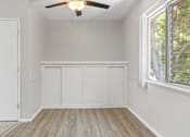 Thumbnail 3 of 23 - A room with a ceiling fan and a window with a view of trees.