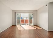 Thumbnail 6 of 47 - A room with a wooden floor and a glass door leading to a balcony.