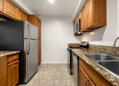 Thumbnail 3 of 44 - A kitchen with a black refrigerator and wooden cabinets.
