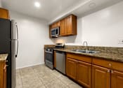Thumbnail 4 of 44 - A kitchen with a black refrigerator and brown cabinets.