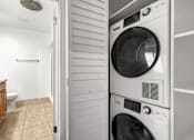 Thumbnail 7 of 44 - A white washing machine is in a small room with a toilet and a shower.