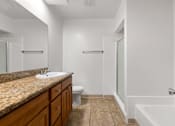 Thumbnail 8 of 44 - A bathroom with a marble countertop and a white bathtub.