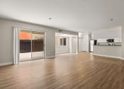 Thumbnail 15 of 38 - an empty living room with a sliding glass door and a kitchen in the background