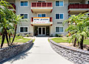 Thumbnail 65 of 69 - A building with a sign that says "NOW LEASING" is surrounded by palm trees.