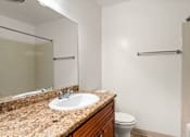 Thumbnail 17 of 69 - A bathroom with a granite countertop and a white toilet.