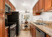 Thumbnail 14 of 69 - A kitchen with brown cabinets and a black refrigerator.