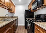 Thumbnail 44 of 69 - a kitchen with wood cabinets and black appliances at Lombardi Apartments, Woodland Hills, CA, 91367