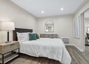 Thumbnail 5 of 55 - A bedroom with a bed, nightstand, and a mirror.
