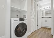 Thumbnail 7 of 55 - A white washing machine is in a small laundry room.
