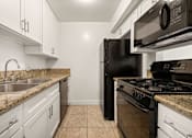 Thumbnail 3 of 40 - A kitchen with a black refrigerator and stove top oven.