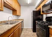 Thumbnail 31 of 40 - A kitchen with a black refrigerator and stove.