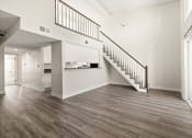 Thumbnail 8 of 40 - an empty living room with a staircase and a kitchen in the background