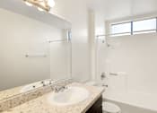Thumbnail 9 of 36 - A white bathroom with a sink, mirror, toilet, and bathtub.