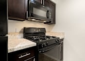 Thumbnail 4 of 36 - A black stove top oven with a microwave above it.