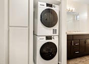 Thumbnail 6 of 36 - A white front loading washing machine is stacked on top of a smaller white top loading washing machine.