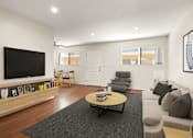 Thumbnail 1 of 36 - A living room with a grey couch, a wooden coffee table, and a flat screen TV mounted on the wall.