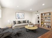 Thumbnail 5 of 36 - A living room with a grey couch, a grey chair, a black coffee table, a lamp, a book, a plant, a picture on the wall, a white door, and a bookshelf.