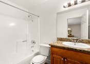 Thumbnail 10 of 54 - A white toilet sits next to a white bathtub in a bathroom.