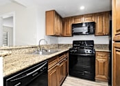 Thumbnail 40 of 54 - a kitchen with wooden cabinets and a black stove top oven at Woodland Trio Apartments, North Hollywood