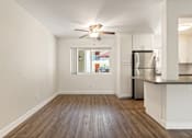 Thumbnail 15 of 44 - an empty living room with a kitchen and a ceiling fan at Parkway Terrace Apartments, Culver City, California