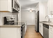 Thumbnail 16 of 44 - an empty kitchen with stainless steel appliances and white cabinets at Parkway Terrace Apartments, Culver City, California