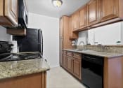 Thumbnail 12 of 41 - Mar Vista CA Apartments -Furnished Kitchen with Convenient Amenities Like Fridge, Microwave, and Stove and Upgraded Cabinets and Granite Countertops