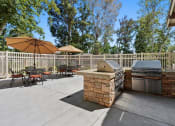 Thumbnail 58 of 60 - Outdoor BBQ Area with Multiple Grills and Shaded Table Seating at The Meadows at Westlake Village Apartments,California, 91361