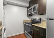 Thumbnail 44 of 60 - Kitchen with White Walls, Stainless Steel Appliances, Marble Countertops, and Espresso Cabinetry at The Meadows at Westlake Village Apartments, CA, 91361