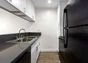 Thumbnail 15 of 41 - Apartments in West Hills for Rent - Topanga Canyon - Interior View of Kitchen with Black Appliances, Gray Countertops, and White Cabinetry