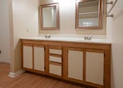 Thumbnail 22 of 25 - A bathroom vanity with a white countertop and wooden cabinets.