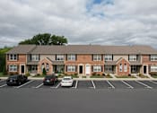 Thumbnail 30 of 34 - A large brick building with a parking lot in front.