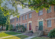 Thumbnail 17 of 17 - A row of red brick houses with green doors and windows.