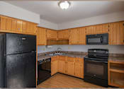 Thumbnail 93 of 94 - A kitchen with wooden cabinets and black appliances.