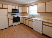 Thumbnail 21 of 25 - A kitchen with wooden floors and white appliances.