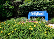 Thumbnail 4 of 12 - A blue sign that says "The Highlands" is surrounded by greenery and yellow flowers.