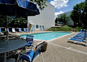 Thumbnail 2 of 12 - A pool area with blue chairs and a table.